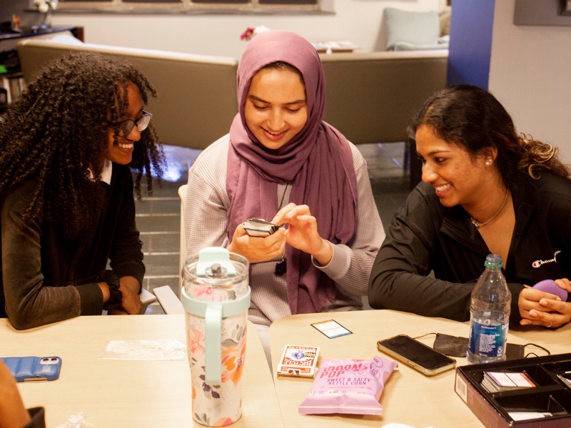 Three students smiling while looking at taboo cards