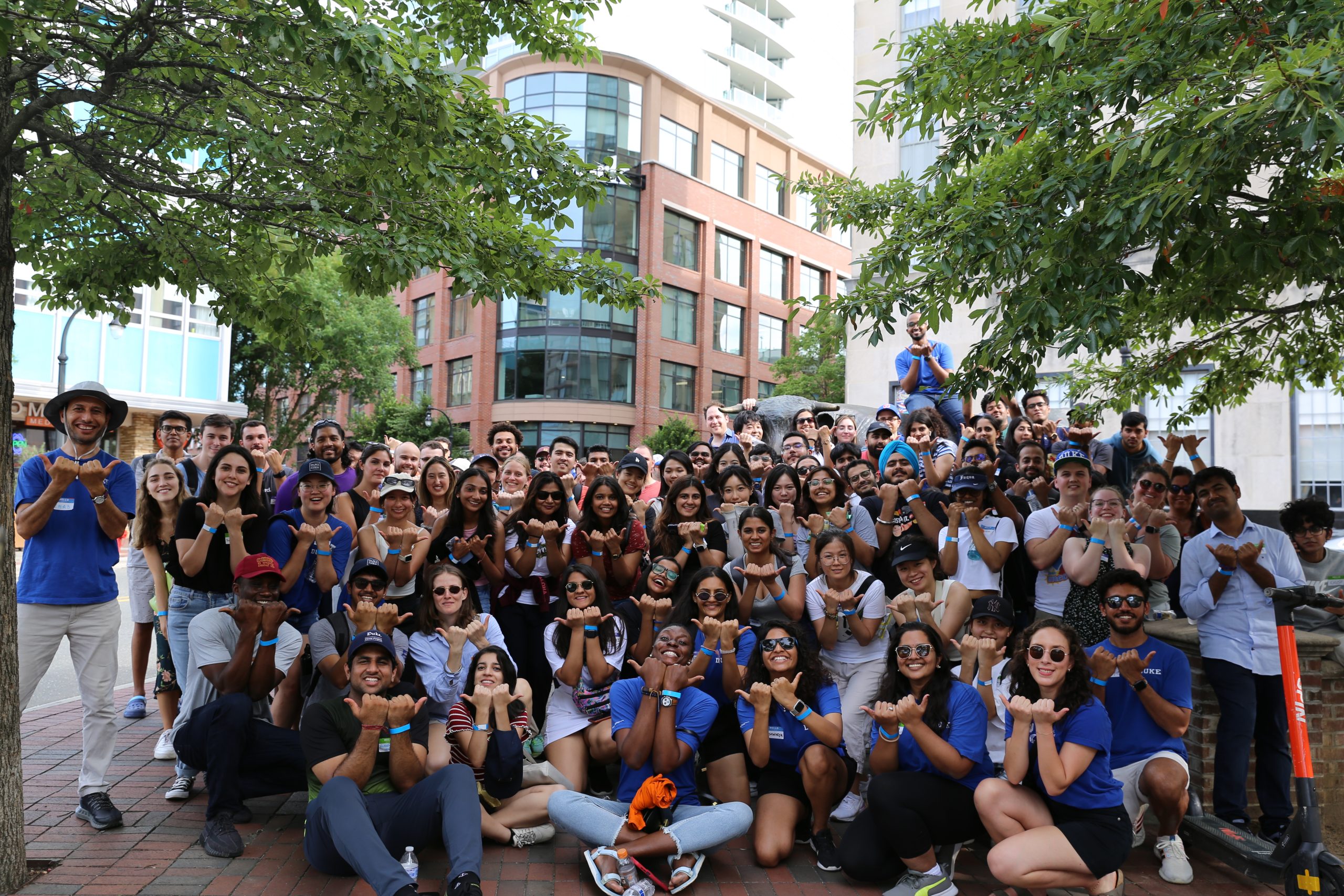 dozens of students posing with the durham bull hand signal in downtown durham