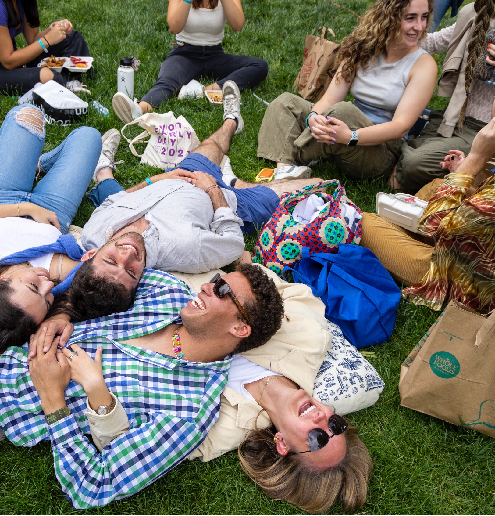 several students lay on the quad on a sunny day laughing and picnicing