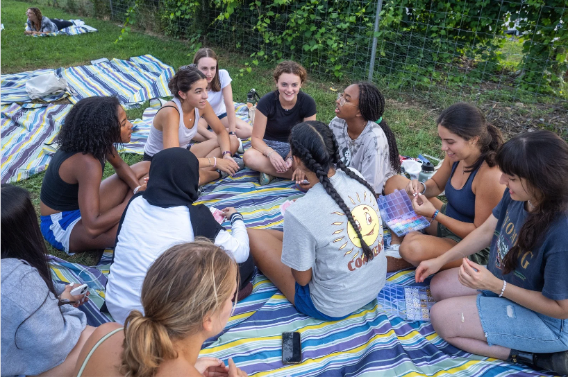 several students sit together on a blanket talking