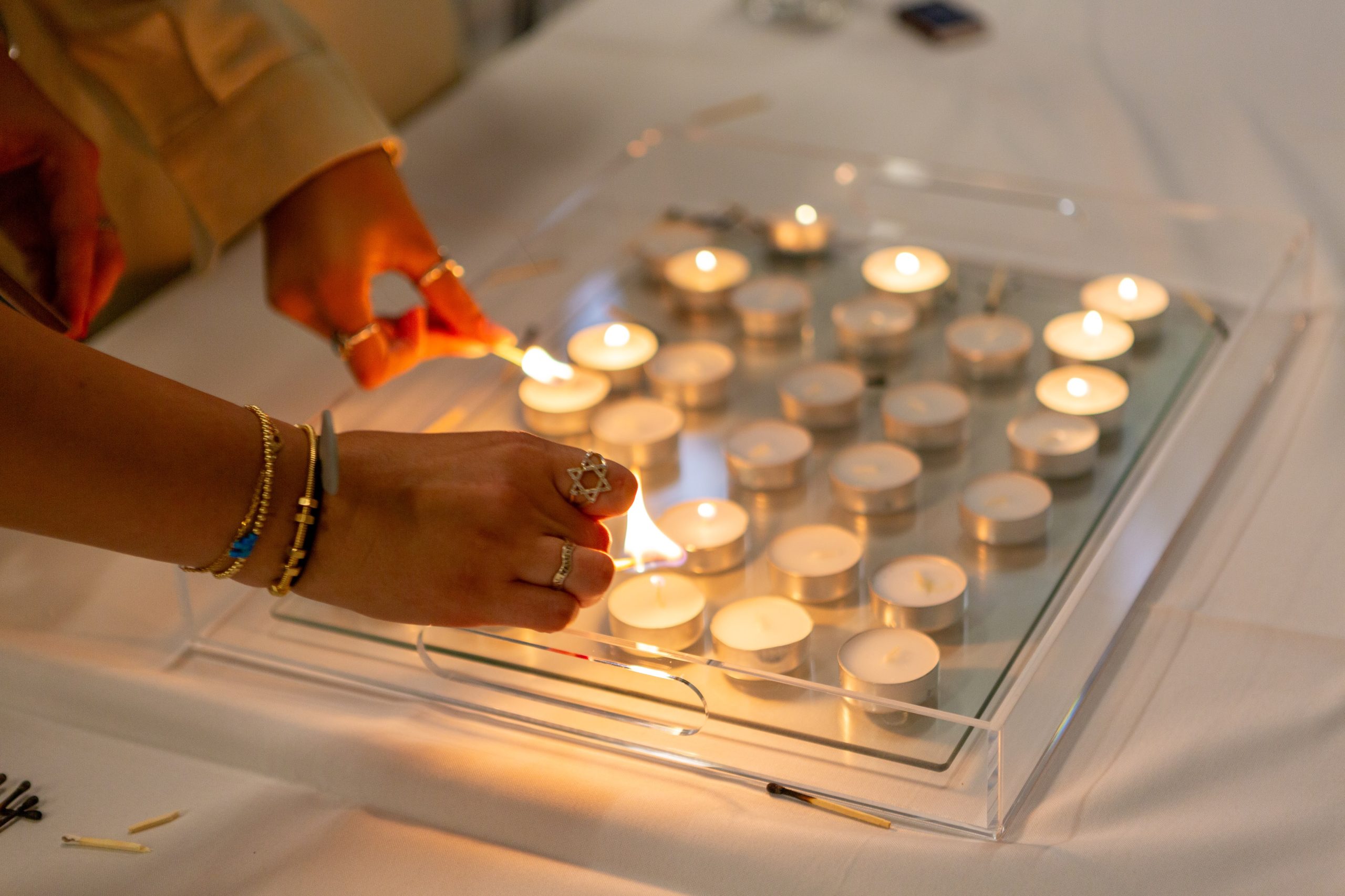 hand lighting shabbat candle; star of david ring on finger